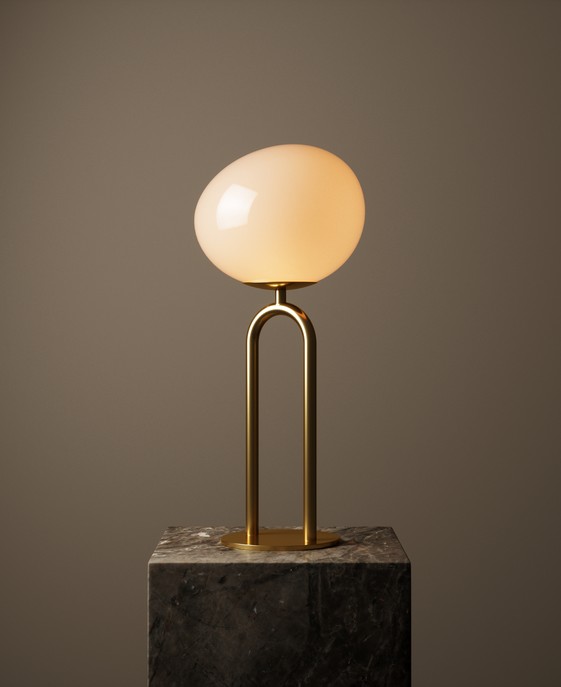 Stolová lampa Shapes od Nordluxu s tienidlom z opálového skla v kombinácii s mosadznou základňou. Tienidlo asymetrickej formy dodáva priestoru mäkkú rozptýlenú žiaru.