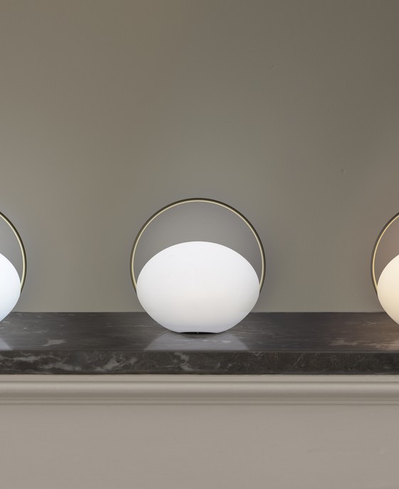 Prenosné svetlo Orbit od značky Umage v bielom vyhotovení s mosadznými detailmi. Tri intenzity stmievania, vhodné do interiéru aj exteriéru.