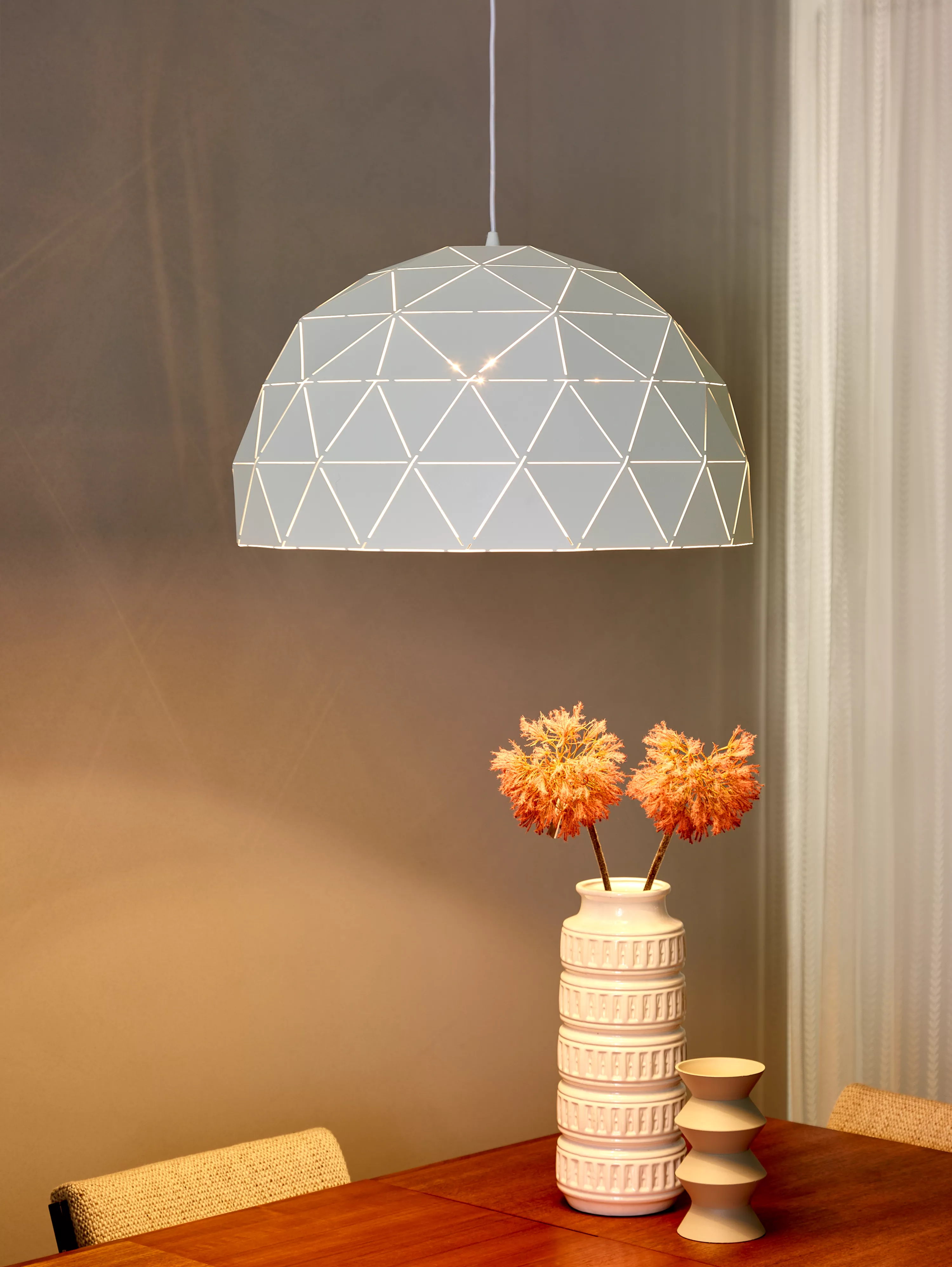 Výrazné závesné svietidlo v bielej farbe s trojuholníkovou perforáciou sa hodí nad jedálenský stôl alebo do obývačky.