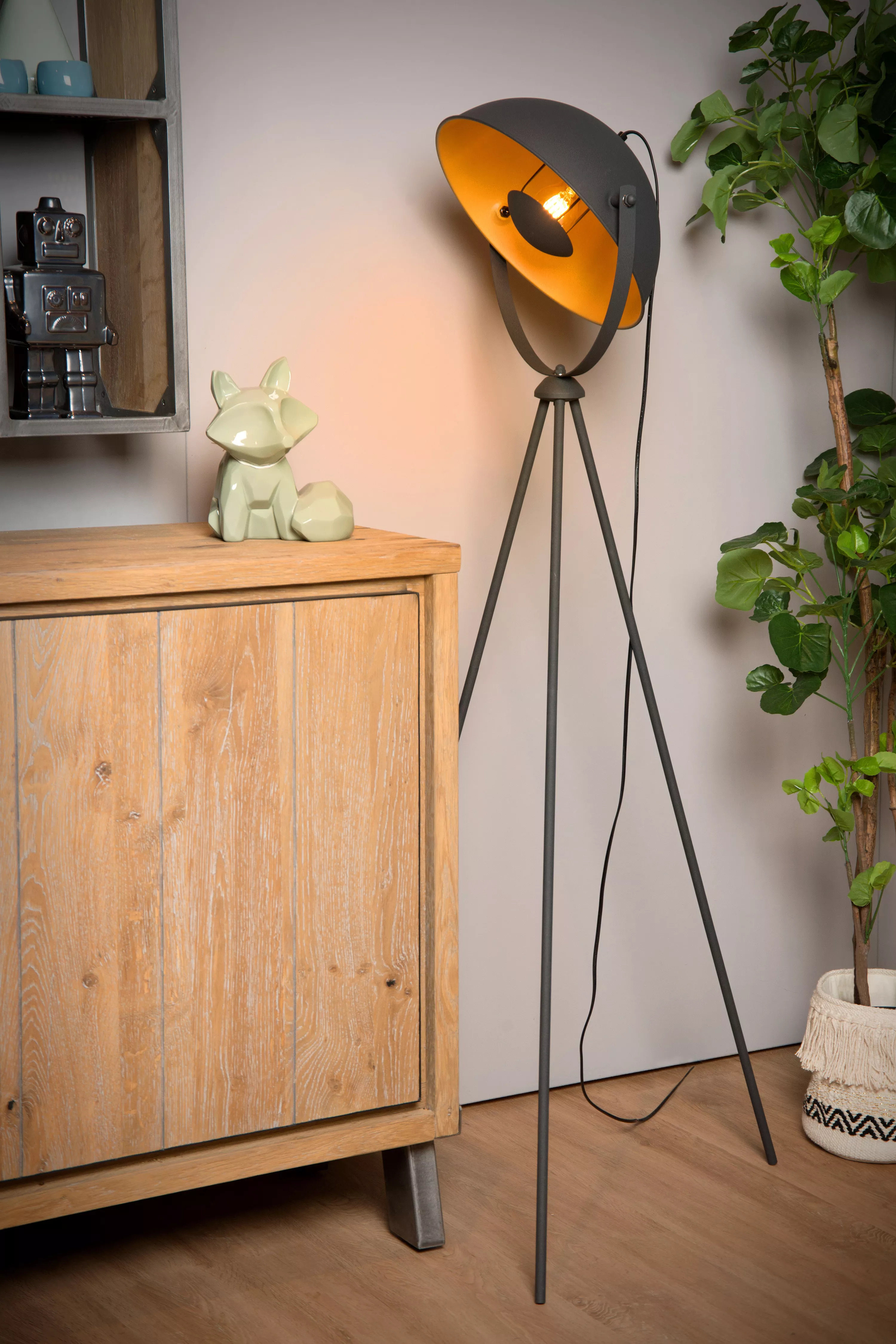 Čierna stojacia lampa Alvaro s mosadznými detailmi na troch nohách navodí v obývacej izbe alebo v čitateľskom kútiku príjemnú atmosféru .