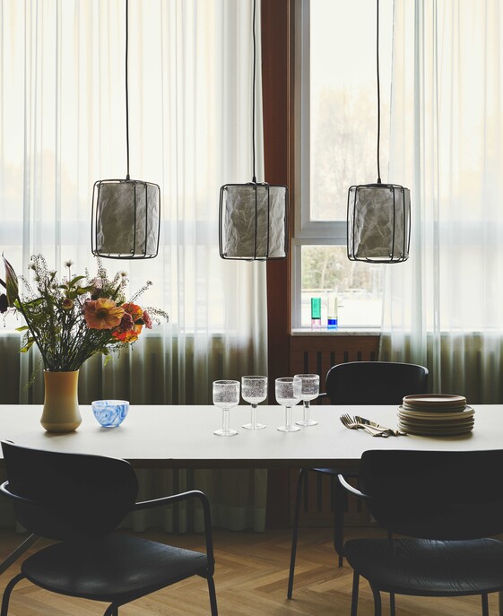 Závesné svietidlo Cardine inšpirované japonskou filozofiou a severským minimalizmom. Tri biele zvlnené tienidlá zavesené na čiernych kovových drôtoch poskytujú rozptýlené svetlo, ideálne nad jedálenský stôl.