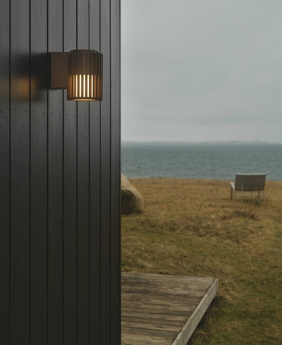 Vonkajšie nástenné svetlo Aludra Seaside od Nordluxu v modernom minimalistickom dizajne. Vďaka svojmu špecifickému tvaru vytvára v okolí hru svetla a tieňa. Vyrobené z odolného materiálu, dostupné v troch farbách – čiernej, antracitovej a metalickej hnedej.