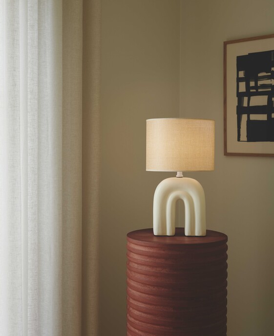 Stolová lampička Haze kombinuje keramiku a ľanové tienidlo, ktoré dodáva interiéru mäkké svetlo. K dispozícii v béžovej farbe.
